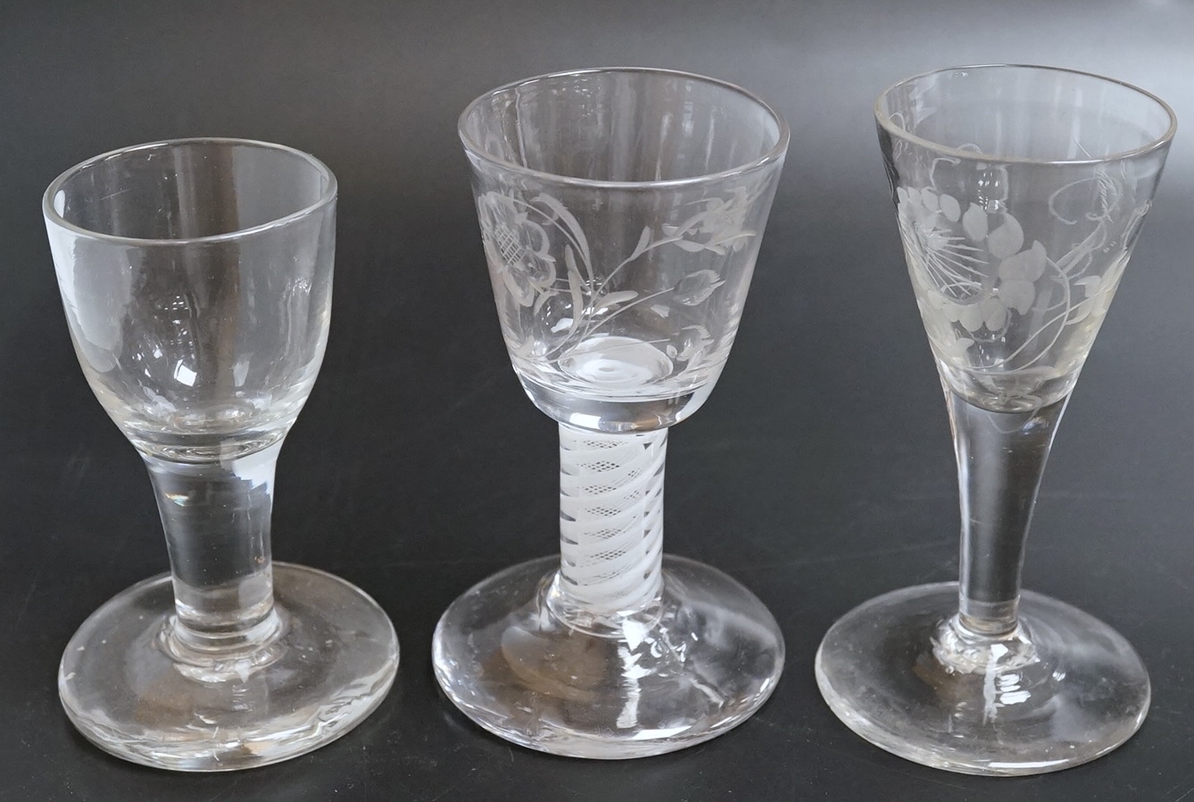 Two George III firing glasses, one with DSOT stem, together with a gin glass with engraved bowl, tallest 11.5cm high (3)